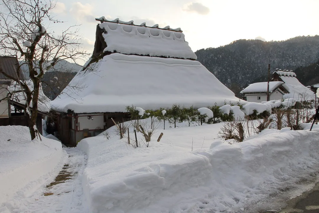 通路が除雪された茅葺家屋