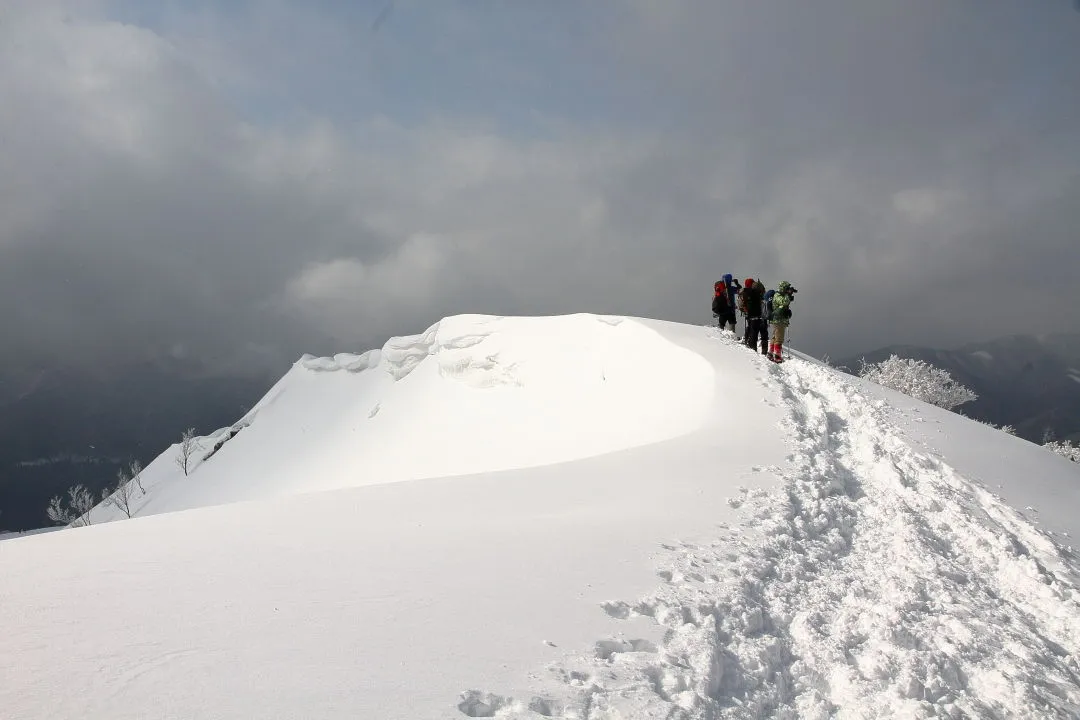 陽の射す山頂を見上げる登山者